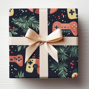 K&ouml;nnte beinhalten: Ein Geschenk, verpackt mit einem marineblauen Hintergrund, der mit Videospiel-Controllern, immergr&uuml;nen Zweigen und roten Beeren gemustert ist. Das Geschenk ist mit einem cremefarbenen Band und einer Schleife gebunden, was eine festliche und verspielte &Auml;sthetik erzeugt.