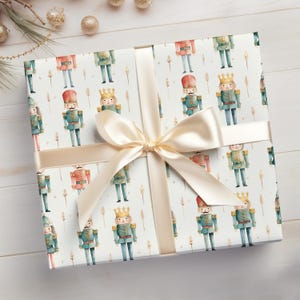 May include: White gift wrap with a repeating pattern of watercolor nutcracker soldiers. The wrapping paper is tied with a cream-colored satin ribbon.