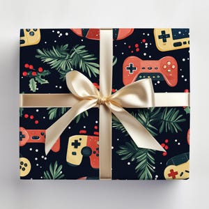 K&ouml;nnte beinhalten: Ein verpacktes Geschenk mit dunkelblauem Hintergrund, das ein Muster aus roten und gelben Videospiel-Controllern sowie gr&uuml;ne Zweige und rote Beeren zeigt. Das Geschenk ist mit einem goldenen Band und einer Schleife gebunden.