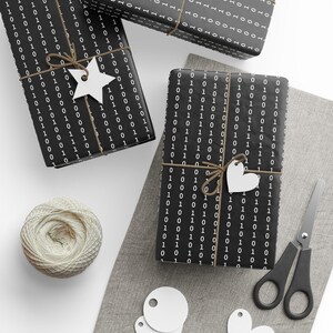 May include: Three black and white gift boxes wrapped in paper with a repeating pattern of 0s and 1s. The boxes are tied with twine and decorated with white paper stars and hearts.