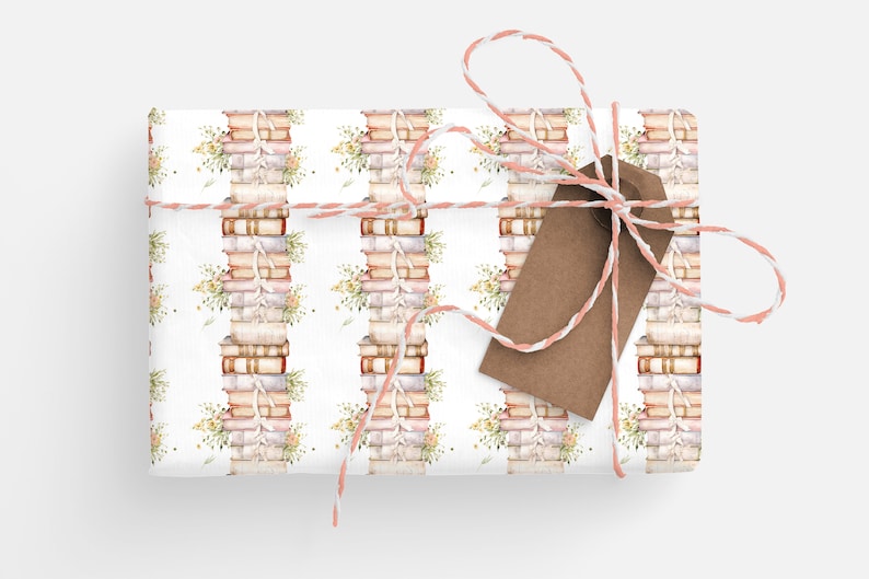 May include: A white gift box wrapped in a pattern of stacked books with floral accents. The box is tied with a pink and white twine bow and a brown gift tag.
