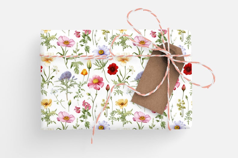 May include: A gift wrapped in white paper with a floral pattern. The paper features a variety of flowers in pink, red, yellow, and purple. The gift is tied with a pink and white twine and a brown gift tag.