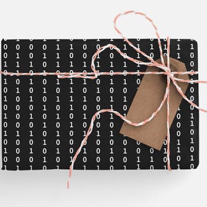 May include: A black gift box with a white binary code pattern wrapped with pink and white twine and a brown gift tag.