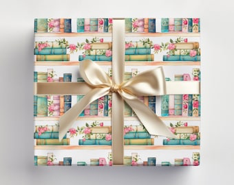 May include: White wrapping paper with a repeating pattern of watercolor painted books on shelves with pink and green flowers. A gold ribbon is tied around the paper.