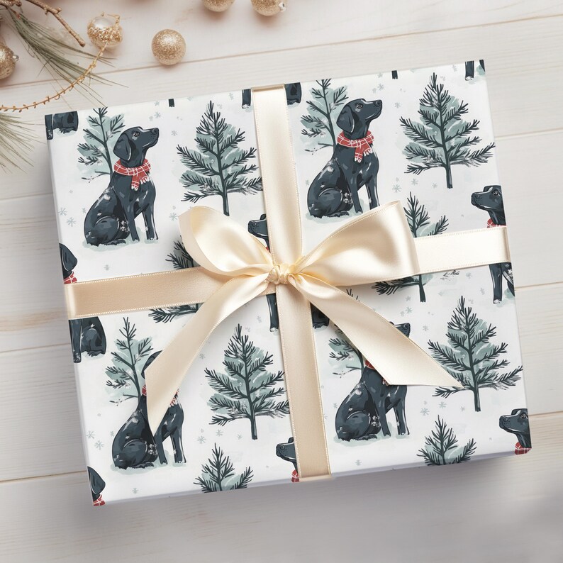 K&ouml;nnte beinhalten: Ein Geschenk, verpackt mit einem cremefarbenen Band und einer Schleife. Das Geschenkpapier zeigt ein sich wiederholendes Muster aus schwarzen Hunden mit roten Schals und gr&uuml;nen Weihnachtsb&auml;umen auf wei&szlig;em Hintergrund. Das Geschenk liegt auf einer hellen Holzoberfl&auml;che.