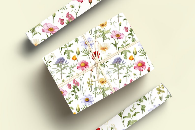 May include: A white gift box wrapped in floral patterned paper. The paper features a repeating pattern of pink, red, yellow, and blue flowers with green leaves. The box is tied with a natural twine bow.