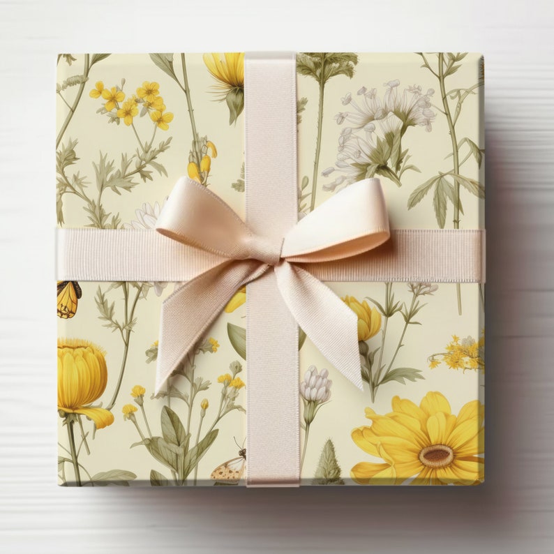 Pu&ograve; includere: Una scatola regalo avvolta in carta con motivo floreale giallo con un nastro di raso color crema legato in un fiocco.
