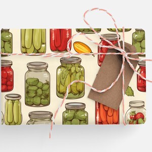 May include: A cream-colored gift wrap with a repeating pattern of jars filled with various pickled vegetables and fruits. The jars are drawn in a cartoon style and include red tomatoes, green cucumbers, green olives, and red peppers.