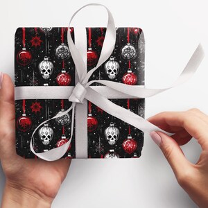 May include: Black and white gift wrap with a repeating pattern of red and white baubles and skulls. The gift is wrapped with a white ribbon.