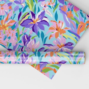 May include: A roll of blue wrapping paper with a floral pattern featuring pink, orange, purple, and green flowers. The paper is rolled up and partially unrolled, showing the pattern.