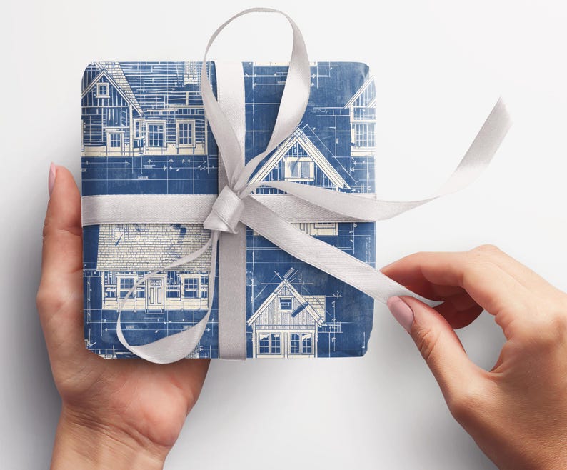 May include: A gift wrapped in blue and white wrapping paper with a blueprint design of houses. The gift is tied with a white satin ribbon.