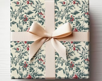 May include: A square gift box wrapped in cream-coloured paper with a repeating pattern of green leaves and red berries. A cream-coloured ribbon is tied in a bow around the box.