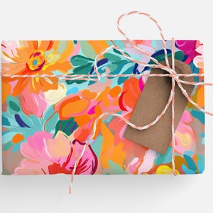 May include: A gift box wrapped in colourful floral patterned paper with a brown paper tag tied with a pink and white twine bow.