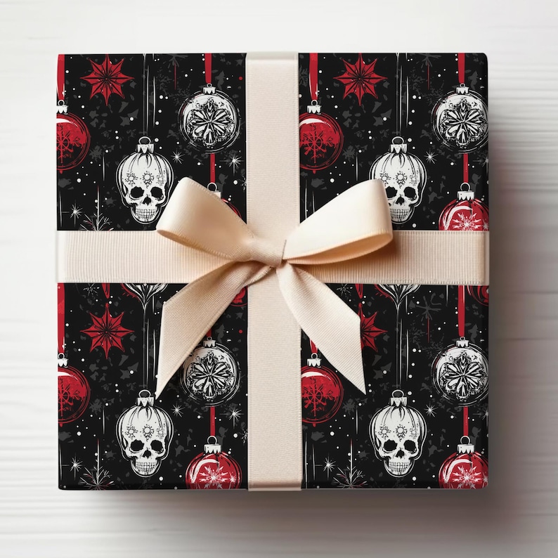 May include: Black and white skull Christmas baubles on a black background with red stars and snowflakes. The baubles are hanging from a white ribbon.