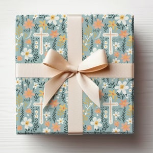 May include: A gift box wrapped in blue and white floral patterned paper with a beige ribbon and bow. The paper features a repeating pattern of white flowers, green leaves, and small crosses.