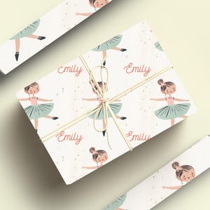 May include: White wrapping paper with a repeating pattern of a ballerina in a green tutu and the name "Emily" printed in pink.