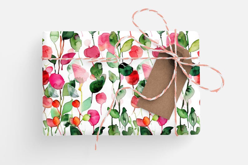 May include: A white gift wrap with a watercolor floral pattern featuring pink and red flowers, green leaves, and white stems. The gift wrap is tied with a pink and white twine and a brown gift tag.
