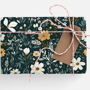 May include: A gift box wrapped in dark green floral wrapping paper with a white and pink twine bow and a brown gift tag. The wrapping paper features a pattern of white and yellow flowers and green leaves.
