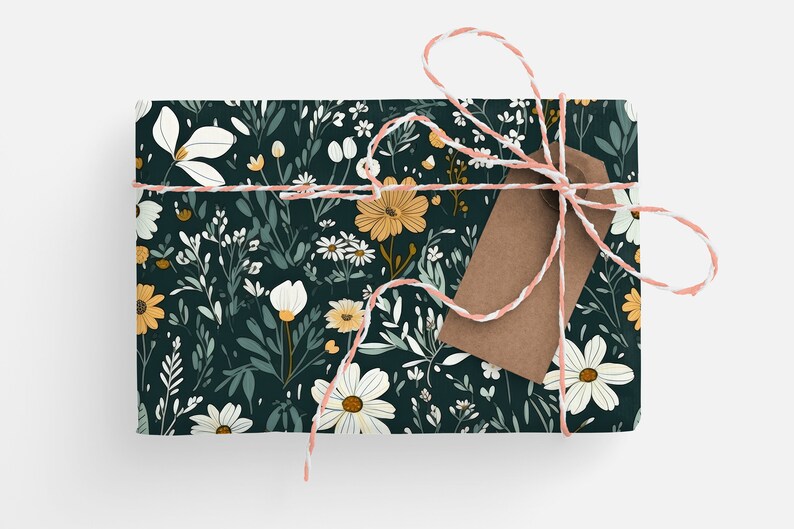 May include: A gift box wrapped in dark green floral wrapping paper with a white and pink twine bow and a brown gift tag. The wrapping paper features a pattern of white and yellow flowers and green leaves.