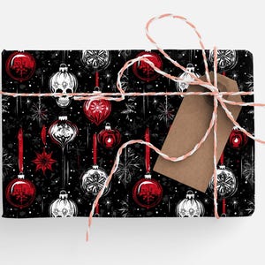 May include: Black and white wrapping paper with a repeating pattern of red and white Christmas baubles, snowflakes, and skulls. The paper is tied with a white twine bow and a brown gift tag.