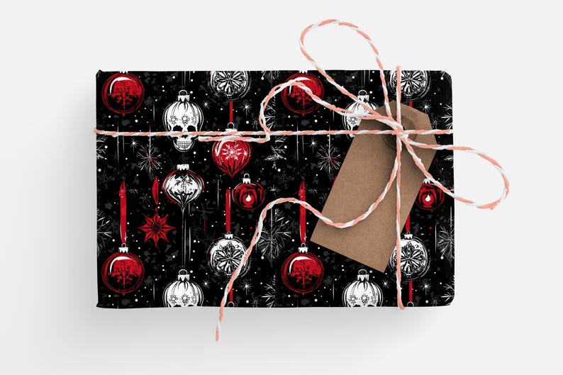 May include: Black and white wrapping paper with a repeating pattern of red and white Christmas baubles, snowflakes, and skulls. The paper is tied with a white twine bow and a brown gift tag.