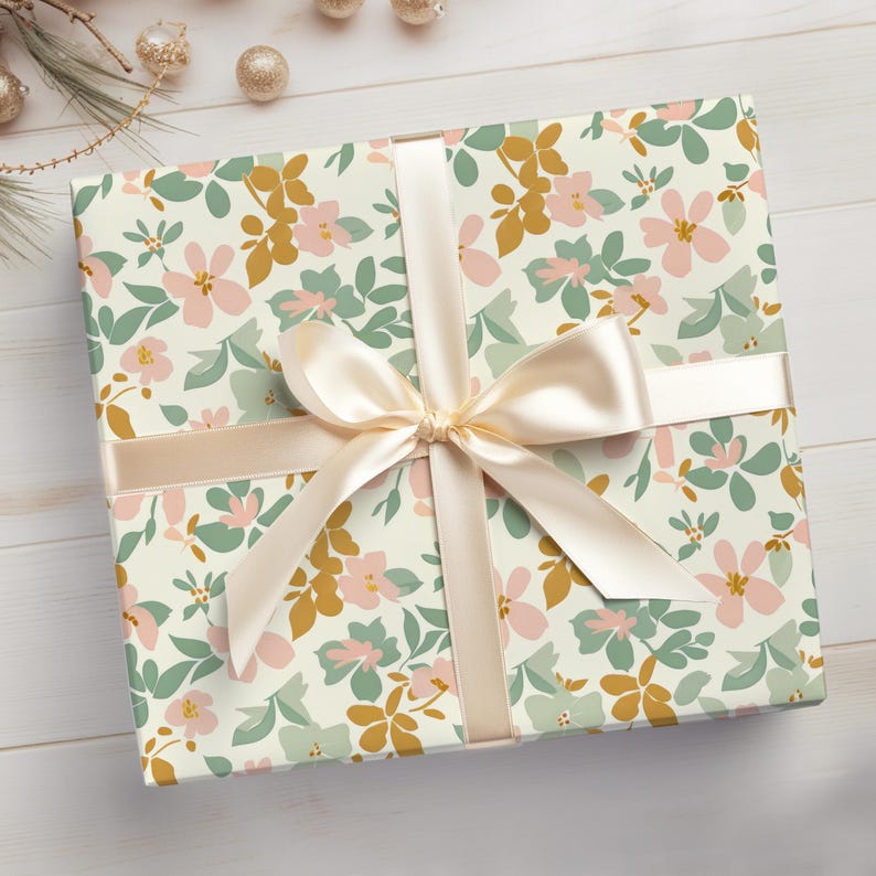 Op de afbeelding: Een cadeaudoos ingepakt in wit, met bloemenpatroon bedrukt papier met een cr&egrave;mekleurig satijnen lint dat in een strik is gebonden.