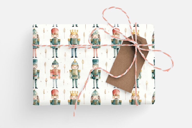 May include: White wrapping paper with a repeating pattern of watercolor nutcracker soldiers. The nutcrackers are wearing blue and red uniforms with gold accents. The paper is tied with a brown and white twine bow.
