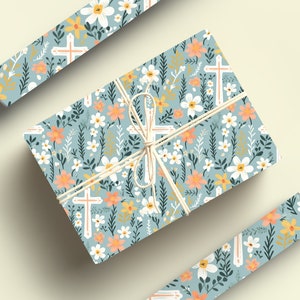 May include: A gift wrapped in blue floral wrapping paper with white crosses and a light brown twine bow. The paper features a repeating pattern of white flowers, orange flowers, green leaves, and white crosses.