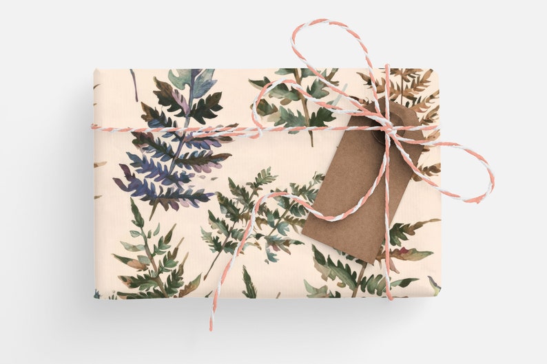 May include: A gift wrapped in cream paper with a watercolor fern pattern. The gift is tied with a pink and white twine and a brown gift tag.