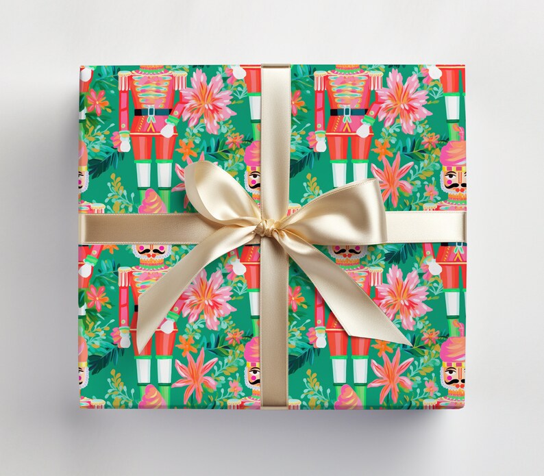 May include: Green wrapping paper with a repeating pattern of nutcracker soldiers and pink flowers. A gold ribbon is tied around the paper.