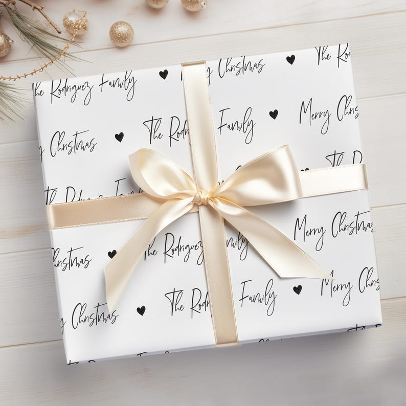 May include: White gift wrap with black text and hearts. The text reads "The Rodriguez Family" and "Merry Christmas".