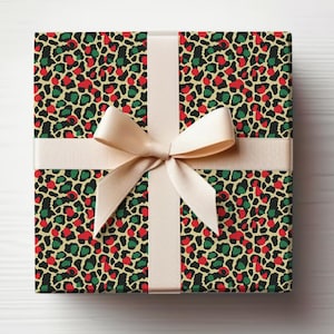May include: A wrapped gift box featuring a festive leopard print pattern in red, green, and black spots on a beige background. The box is tied with a cream-colored ribbon and bow, creating a visually appealing presentation.