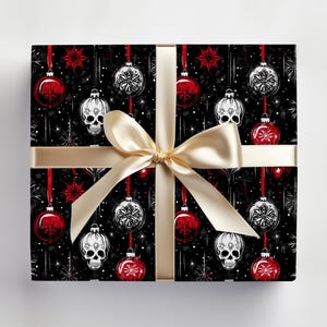 May include: Black and white wrapping paper with a repeating pattern of red and white baubles, stars, and skulls. The paper is tied with a gold ribbon.