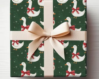 May include: A wrapped gift with a green background featuring a pattern of white geese with red bows. The gift is tied with a beige ribbon and bow, creating a festive and decorative presentation.