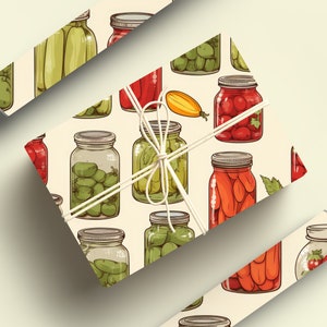 May include: A gift wrapped in white paper with a pattern of various jars of preserved vegetables and fruits. The jars are filled with green beans, tomatoes, peppers, and carrots. The gift is tied with a white ribbon.