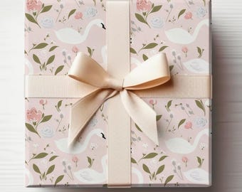 May include: A pink gift box with a white swan and floral pattern. The box is tied with a cream-colored satin ribbon.