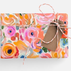 May include: A gift box wrapped in colorful floral patterned paper with a brown gift tag tied with twine.