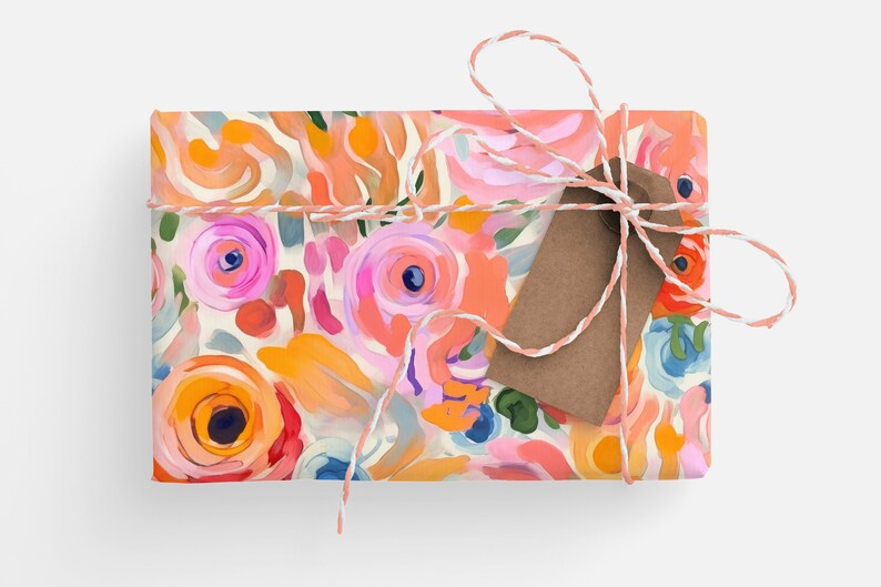 May include: A gift box wrapped in colorful floral patterned paper with a brown gift tag tied with twine.