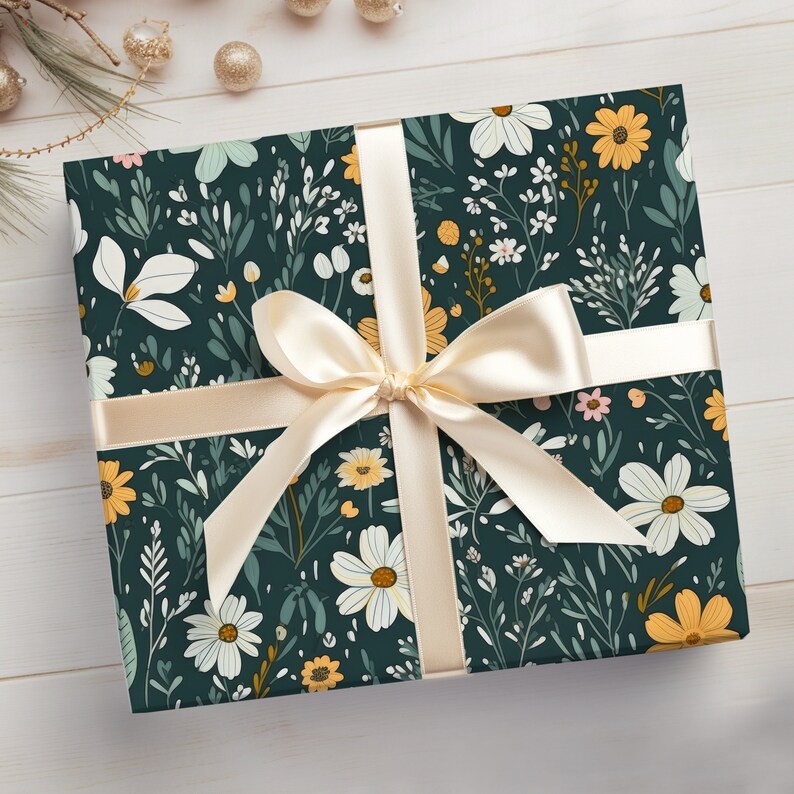 May include: A gift box wrapped in dark green wrapping paper with a floral pattern featuring white, yellow, and pink flowers. A cream-colored satin ribbon is tied in a bow on top of the box.