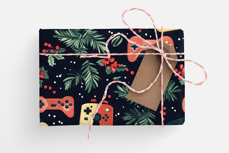 K&ouml;nnte beinhalten: Ein Geschenk mit festlichem Design. Das Geschenkpapier zeigt ein Muster aus roten und gelben Gamecontrollern, gr&uuml;nen Tannenzweigen, roten Beeren und wei&szlig;en Punkten auf einem dunkelblauen Hintergrund. Ein braunes Etikett und rosa-wei&szlig;es Garn vervollst&auml;ndigen das Geschenk.