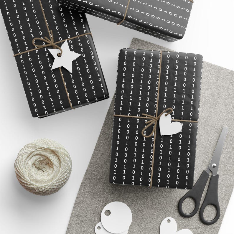 May include: Three black and white gift boxes wrapped in paper with a repeating pattern of 0s and 1s. The boxes are tied with twine and decorated with white paper stars and hearts.