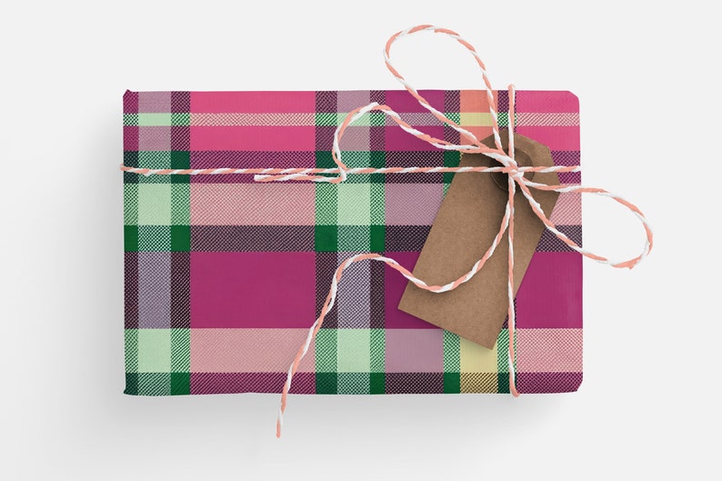 May include: A pink, green, and white plaid gift box tied with a white and peach twine bow and a brown gift tag.