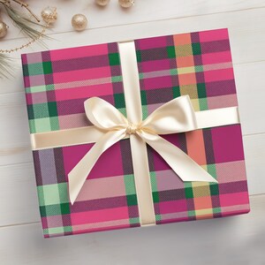 May include: A pink and green plaid gift box with a cream-colored satin ribbon tied in a bow.