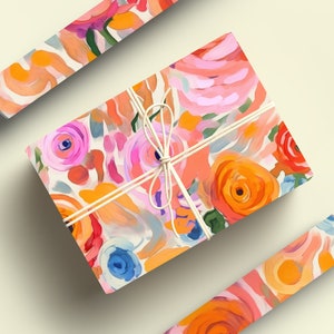 May include: A gift box wrapped in colorful floral patterned paper with a white ribbon. The paper features a bright pink, orange, and blue abstract floral design.
