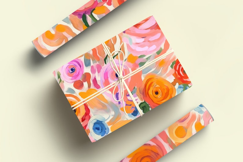 May include: A gift box wrapped in colorful floral patterned paper with a white ribbon. The paper features a bright pink, orange, and blue abstract floral design.