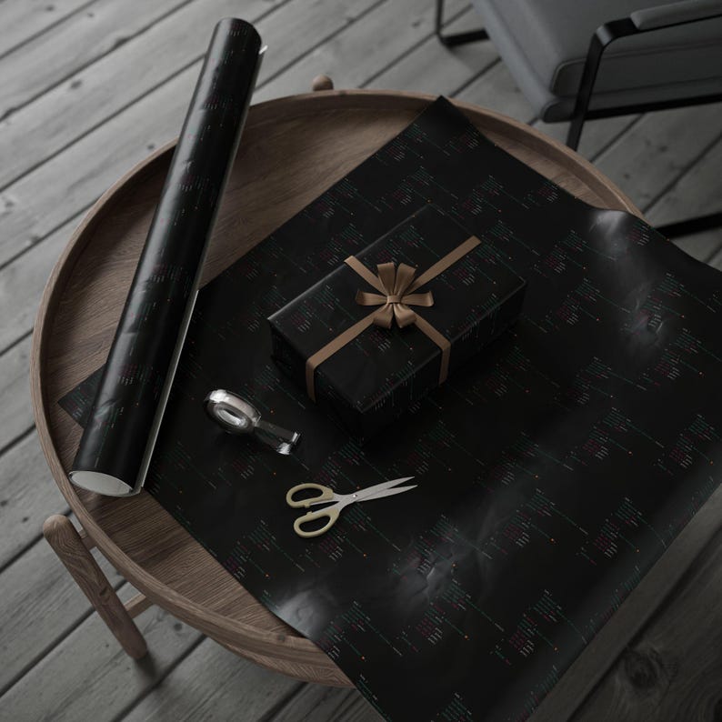May include: A black gift box with a gold ribbon and bow, a roll of black wrapping paper, a pair of gold scissors, and a tape dispenser on a wooden table.