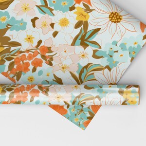 May include: A roll of white wrapping paper with a floral pattern in shades of orange, yellow, blue, and brown. The paper is rolled up and the end is visible.