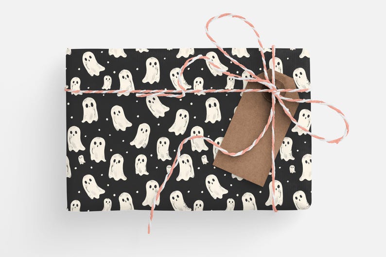 May include: Black gift wrap with a white ghost pattern. The gift is tied with pink and white twine and a brown gift tag.