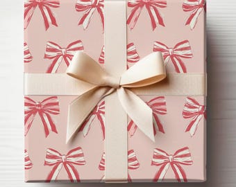 May include: A pink gift box with a white ribbon and a red bow pattern. The box is wrapped in pink paper with a repeating pattern of red bows.