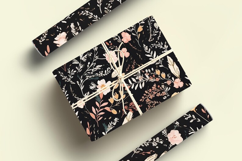 Op de afbeelding: Zwart cadeaupapier met een bloemenpatroon met roze en oranje bloemen en bladeren. Het cadeaupapier is vastgebonden met een wit touwtje.